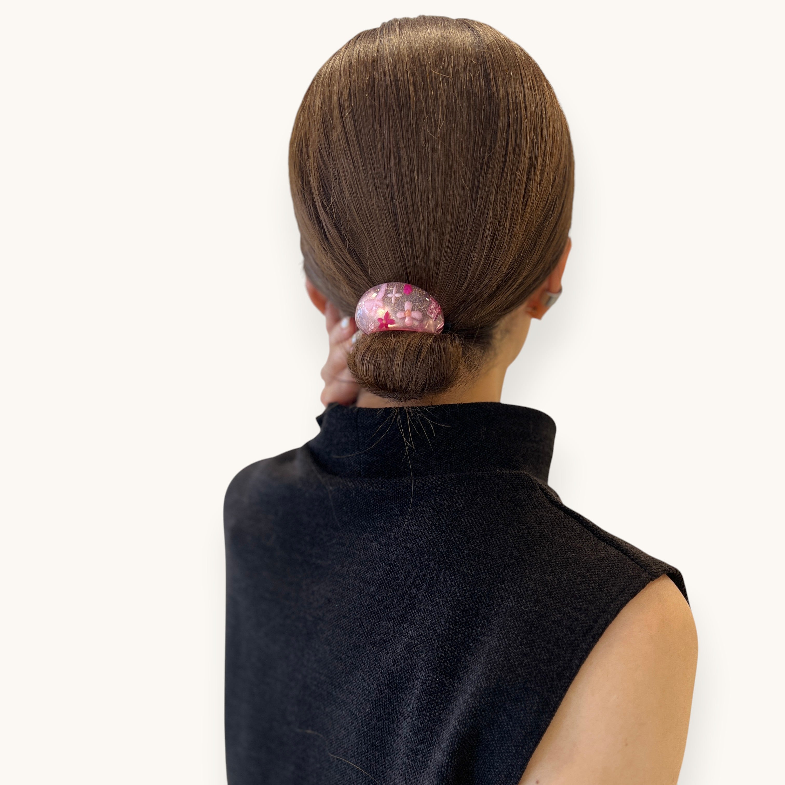 THE HAIR BAR TOKYOのオーバル型ポニー。クリアなルーサイト素材に花と蝶、ラメを閉じ込めた華やかなヘアアクセサリーをシニヨンヘアに着用。