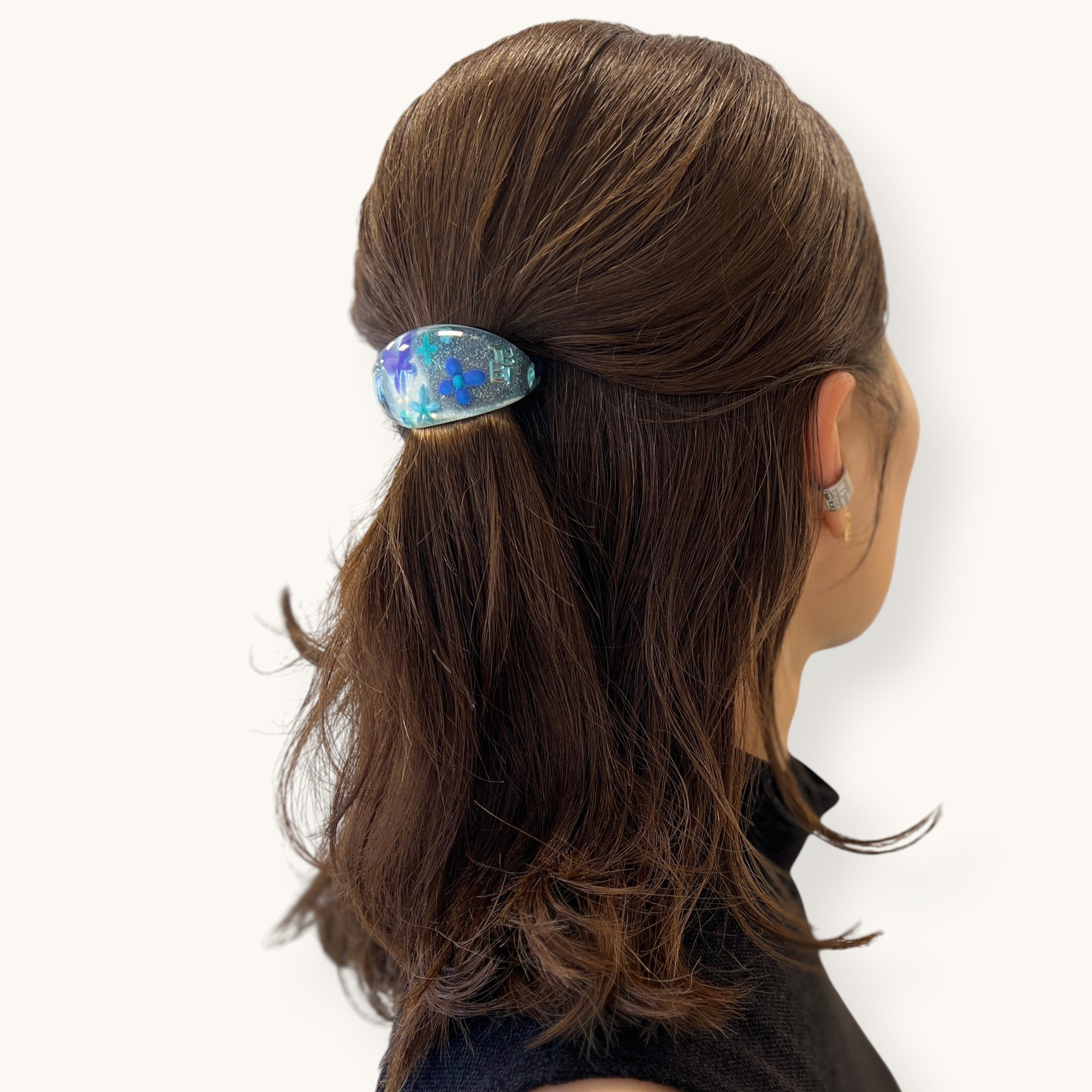 THE HAIR BAR TOKYOのオーバル型ポニー。クリアなルーサイト素材に花と蝶、ラメを閉じ込めた華やかなヘアアクセサリーを髪に着用した様子